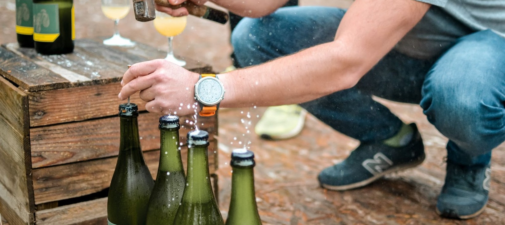 Photo of a person opening bottles of sparkling wine with a hammer and nail.