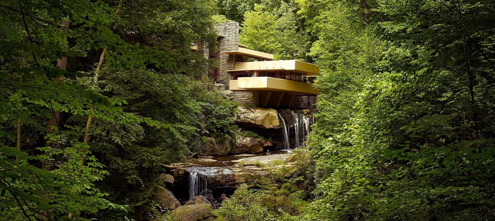 A photo of a building in a forest above a waterfall