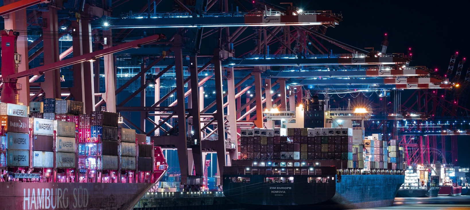 A photo of a harbor with two large container ships ready for unloading.